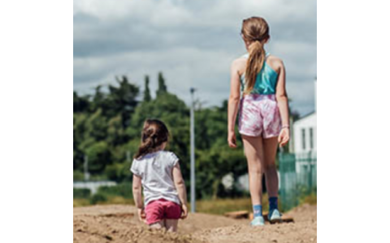 The backs of two young girls walking on sand