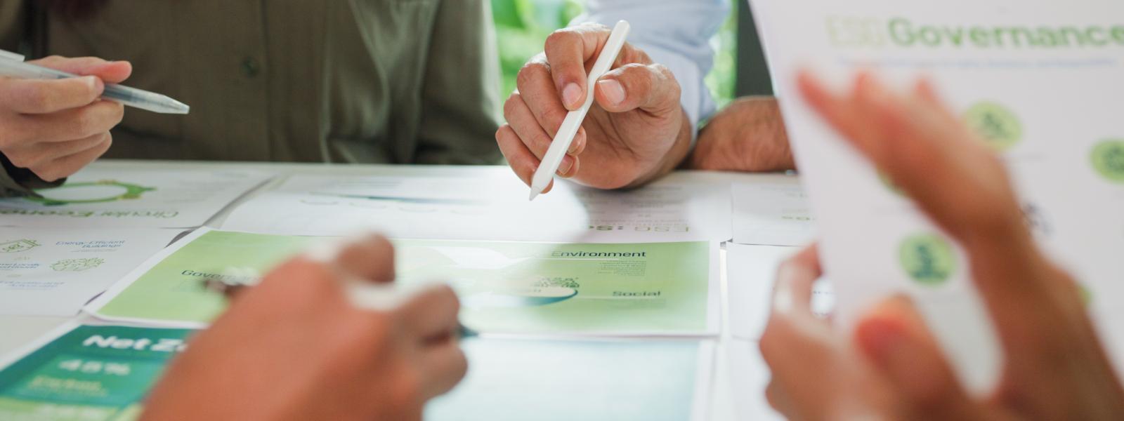 people learning - hands with pens on table with green and white papers