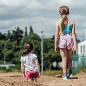 The backs of two young girls walking on sand