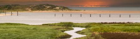 Image of a saltmarsh with an inlet in the foreground and the sea beyond