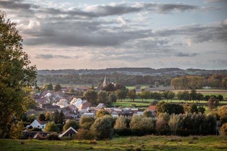 green rolling fields with houses and grey cloudy sky