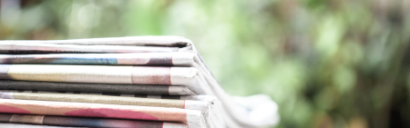 folded up news papers with green background