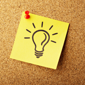 yello post-it-note stuck to cork board with red pin - black outline of lightbulb