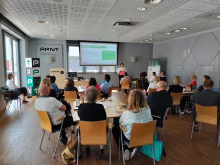 conference room with people sat on wooden chairs looking at presentation