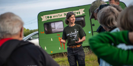 person presenting in front of green caravan