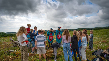 people gathered in green fields under stormy grey sky