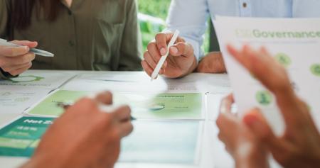 people learning - hands with pens on table with green and white papers