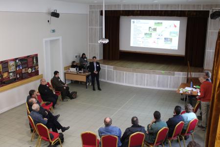 people in half circle listening to a man giving presentation