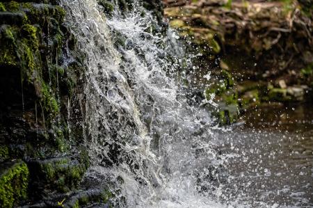 Water from a stream falling down a sharp drop, there is a lot of white spray.
