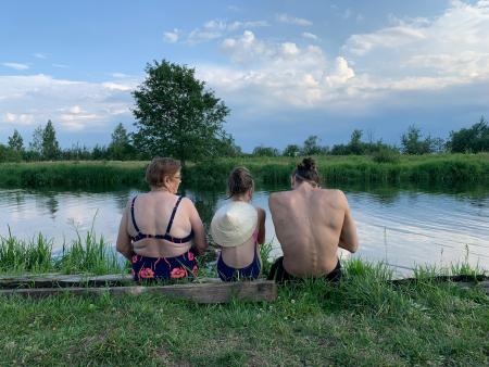 Three people sitting by a river