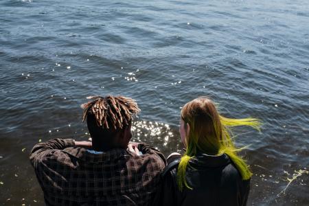 Two people sitting by the water