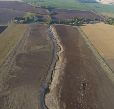 A sinuous stream corridor running through ploughed agricultural land.