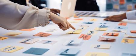 post it notes on a table, someone pointing at one in focus
