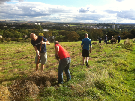 A group of people working with spades on land overlooking Edinburgh.