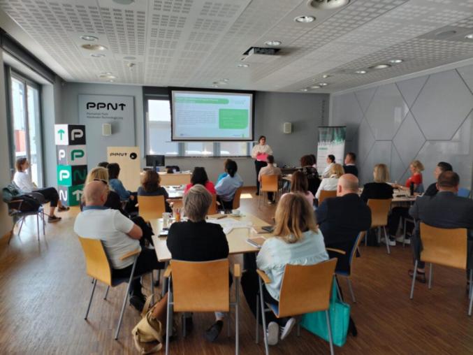 conference room with people sat on wooden chairs looking at presentation