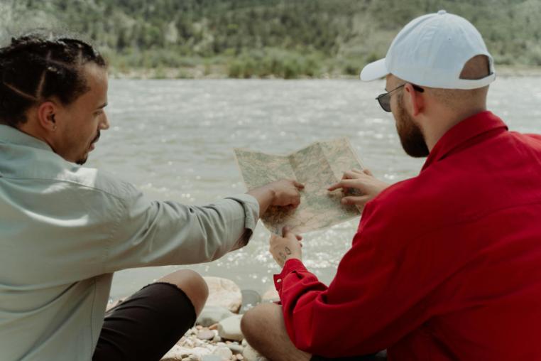 Two people looking at a map by the river