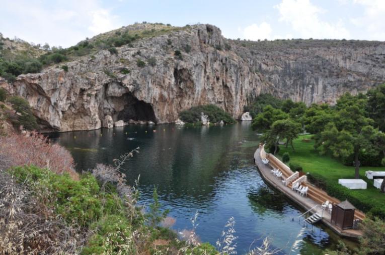 River with a boat on it, there is a rock cliff in the background and greenery on the banksides.