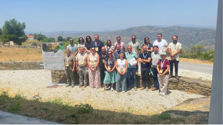Group photograph of stakeholders standing outside with mountains in the background.