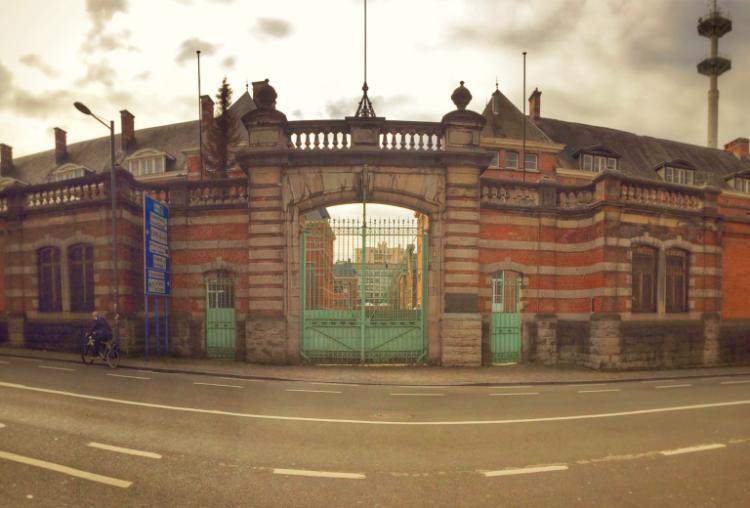 An entry gate at a brick and stone barrack building, the gates are pale green.