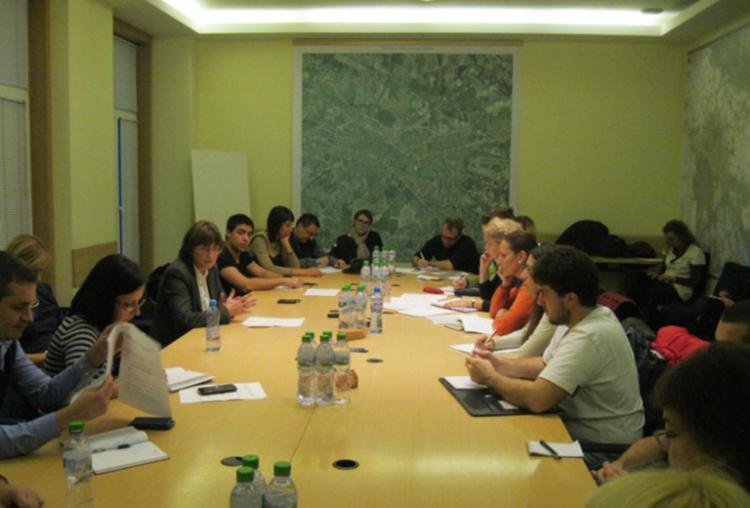 People sitting around a large table looking through paperwork and discussing.