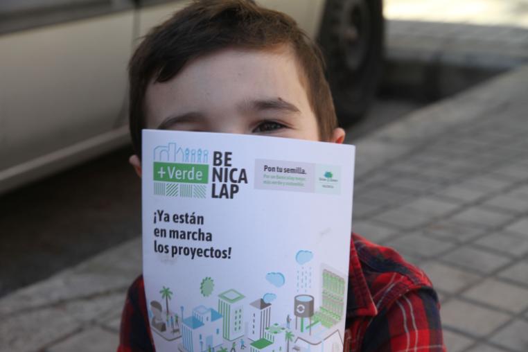 A child holding a project leaflet in front of their face.